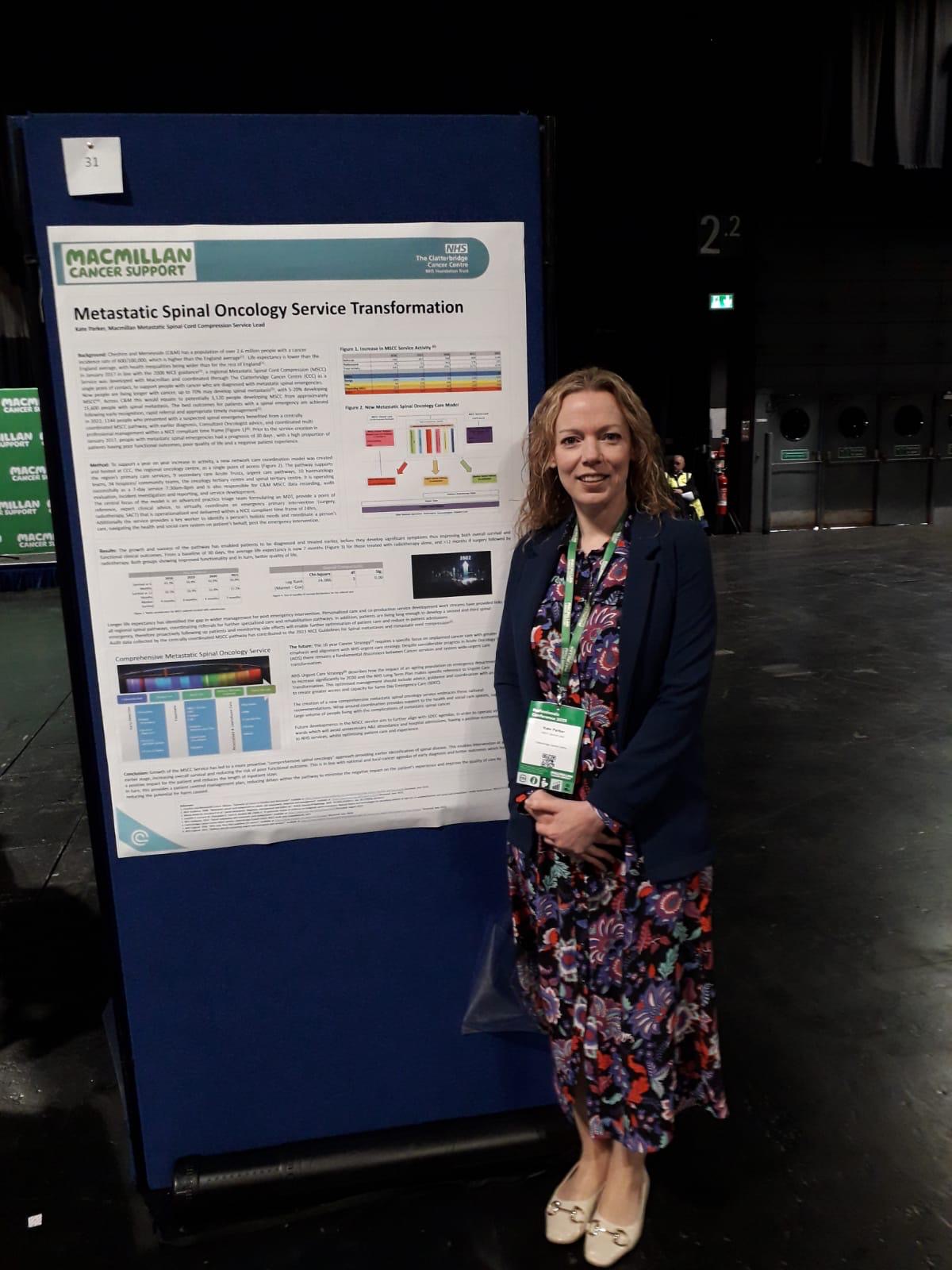 Kate Lacey with a poster of the Metastatic Spinal Cord Compression service