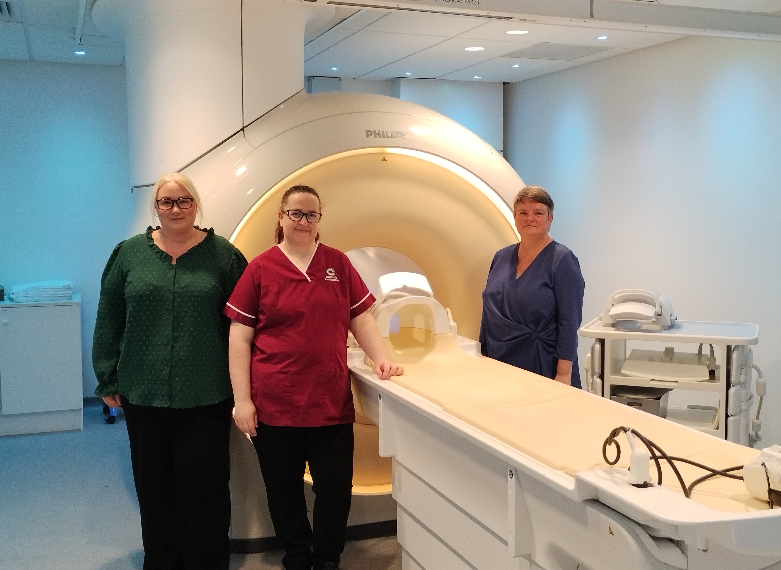 Picture of 3 female staff with a MRI scanning machine