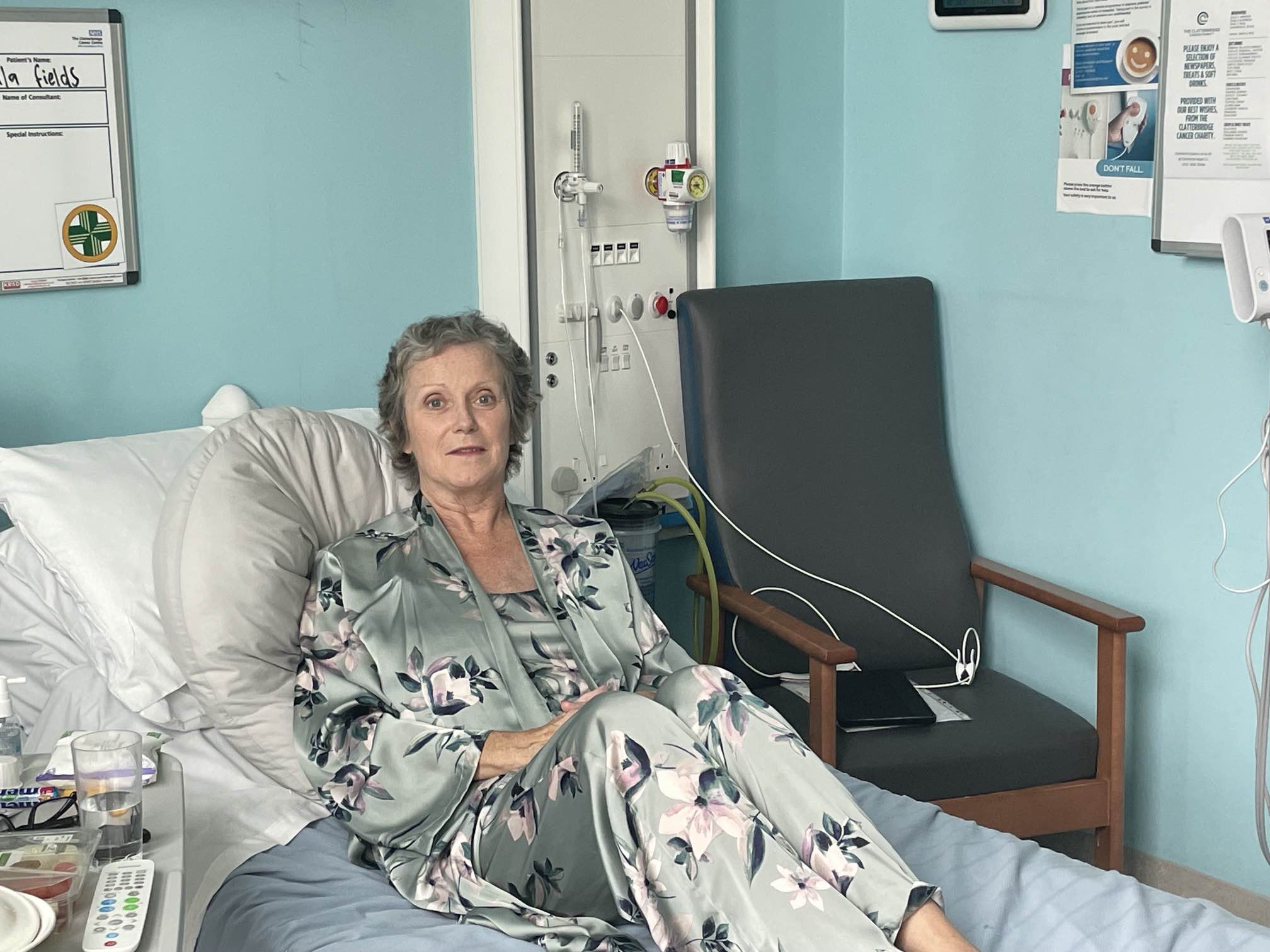 Picture of female patient called Paula Field on her hospital bed. She is wearing light green silk pyjamas and looks happy and relaxed