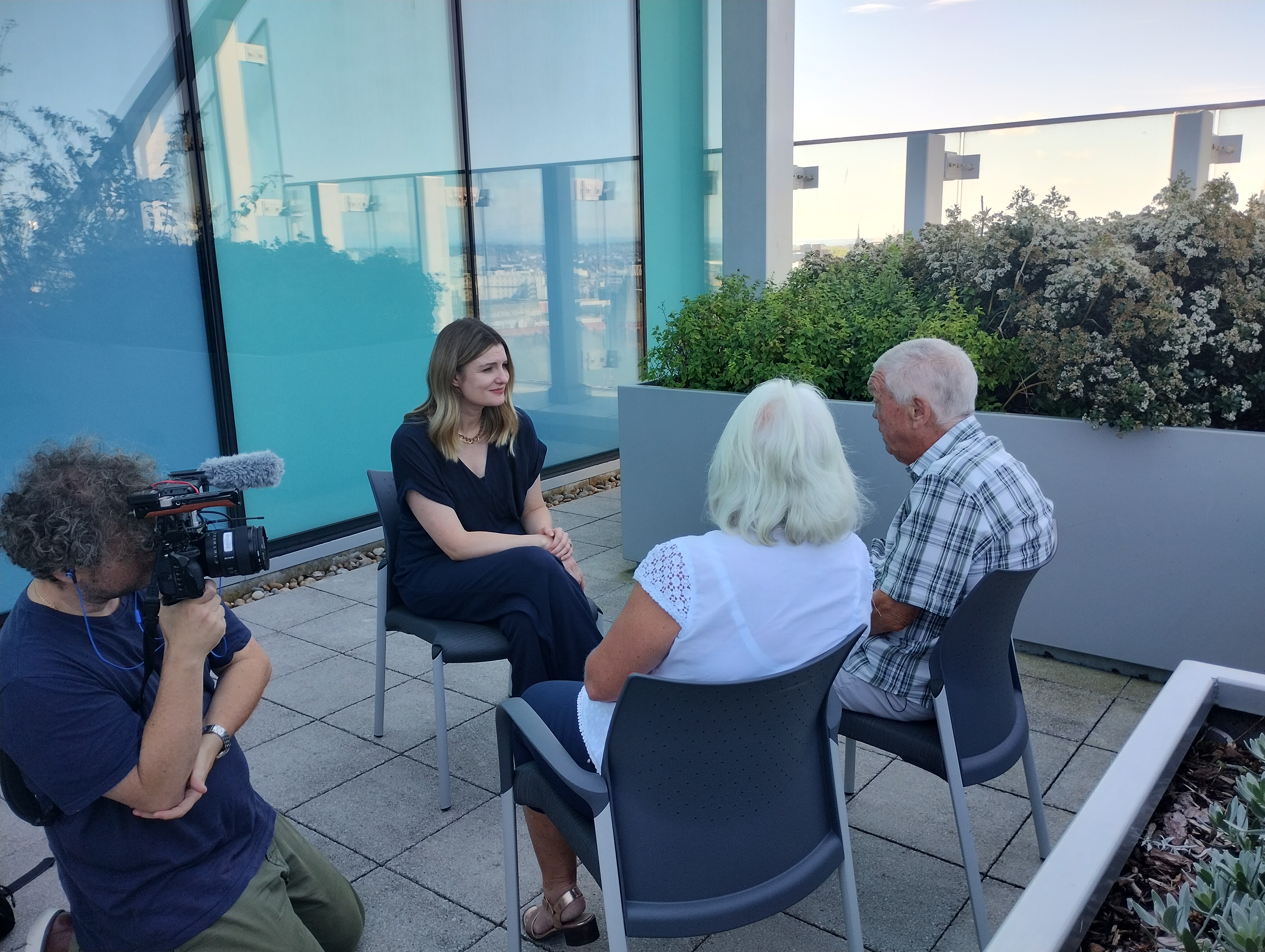 Picture of BBC reporter Anna Collinson interviewing patient Robert and his wife Lynda on the hospital roof terrace