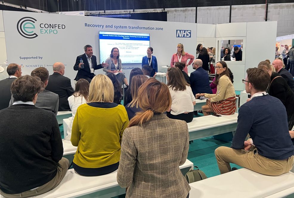 Audience shot showing people attending debate on health inequalities. The picture also shows Liz Bishop (right) with panel members on health inequalities at NHSConfedExpo 2022